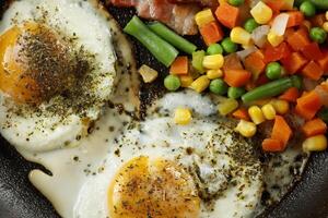 Fried eggs with vegetables in a pan. photo