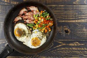 Fried eggs with vegetables in a pan. photo