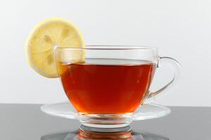 Tea with lemon in a cup. Black tea with a slice of lemon in a glass mug photo