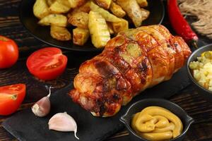 boneless meat roulade with seasonings and garnish. roast pork roulade Porchetta, delicious pork roast with crusty roast potatoes served on wooden table photo
