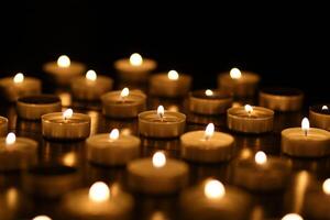 Many burning candles with shallow depth of field. Many small candles on a black background. photo