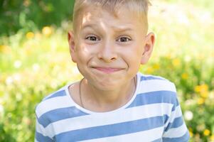 Portrait of a boy making a face in a summer park. Selective focus. photo