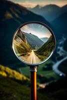 close-up of a magnifying glass in which a beautiful mountain landscape and road are visible photo