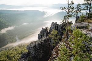The dawn of the day in the mountains, the morning fog creeps in at the bottom of the river valley, the smoke rises from the bottom up into the mountains, a rock cliff. photo