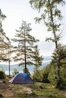 Tourist parking, a tent stands in a clearing in the mountains, forest camping, an awning stretched on top of the tent, trekking in the mountains alone. photo
