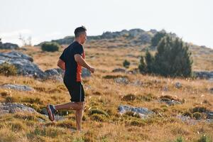 Determined Athlete Running Through Rugged Mountain Terrain at Sunrise. photo