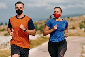 Couple running in nature at morning wearing protective face masks photo