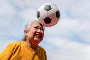 Active senior woman playing football in the urban outdoor court, Asian senior woman with a soccer ball, Healthy life concepts photo
