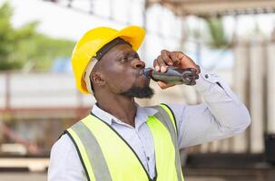 Construction worker drinking cola from a bottle on a site, Worker man take a break and drinking water from bottle photo