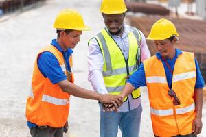 Success Teamwork Concepts, Engineer and workers team joining hands at a construction site photo