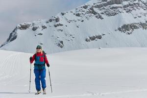 A professional woman skier rejoices after successfully climbing the snowy peaks of the Alps photo