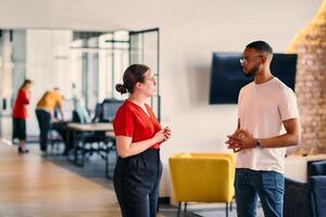 Young business colleagues, including an African American businessman, engage in a conversation about business issues in the hallway of a modern startup coworking center, exemplifying dynamic problem photo