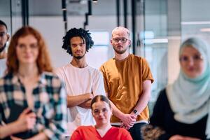 A diverse group of young business people walking a corridor in the glass-enclosed office of a modern startup, including a person in a wheelchair and a woman wearing a hijab photo
