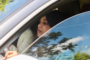 Two Muslim women wearing hijab converse on a smartphone while traveling together in a car through the photo