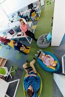 In a modern startup office, a diverse group of young and capable businesspeople engage in lively discussions about various projects, showcasing teamwork, innovation, and entrepreneurial spirit photo