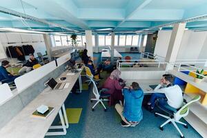 In a modern startup office, a diverse group of young and capable businesspeople engage in lively discussions about various projects, showcasing teamwork, innovation, and entrepreneurial spirit photo