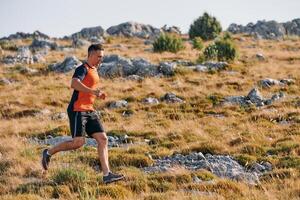 Determined Athlete Running Through Rugged Mountain Terrain at Sunrise. photo