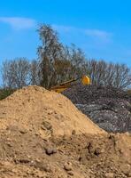 View into a gravel pit with piles of sand and some tire tracks photo