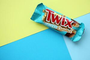 TERNOPIL, UKRAINE - JULY 7, 2023 Twix salted caramel blue wrapper on wooden background. Twix is a chocolate bar made by Mars Inc consisting of biscuit applied with caramel photo
