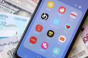 KYIV, UKRAINE - FEBRUARY 28, 2024 Dating apps icons on smartphone display and money bills photo