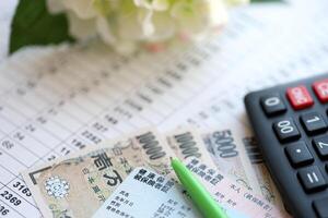 Light blue and red Japan Health Insurance cards on table with japanese yen money and calculator photo