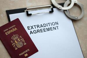 Passport of Spain and Extradition Agreement with handcuffs on table photo