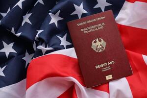 Red German passport of European Union on United States national flag background close up photo