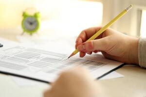 Female student hands testing in exercise and taking fill in exam paper sheet with pencil at school test photo