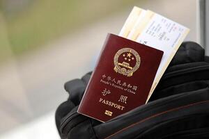 Red passport of People Republic of China with airline tickets on backpack photo