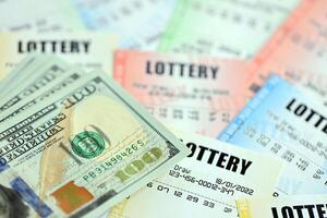 Many lottery tickets and dollar bills on blank bills with numbers for playing lottery photo