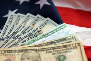 Permanent Resident United States of America Green Card and dollar bills on folded US flag photo