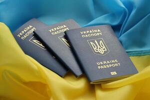 Three Ukrainian biometrical passports on folded waving flag of Ukraine country photo