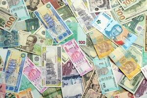 Many banknotes of different currency. Background of big amount of random money bills photo
