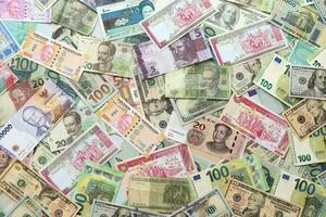 Many banknotes of different currency. Background of big amount of random money bills photo