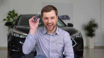 Happy man with keys rejoices in buying a new luxury car at a car dealership video