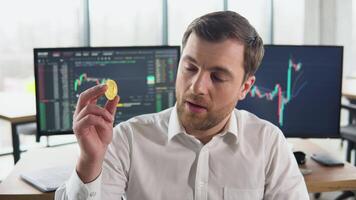 besviken näringsidkare gruvarbetare innehav bitcoin med stock marknadsföra grafer på bakgrund. bitcoin faller. kryptovaluta marknadsföra krascha. bitcoin nedåtgående trend. kris av kryptovaluta video