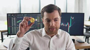 besviken näringsidkare gruvarbetare innehav bitcoin med stock marknadsföra grafer på bakgrund. bitcoin faller. kryptovaluta marknadsföra krascha. bitcoin nedåtgående trend. kris av kryptovaluta video