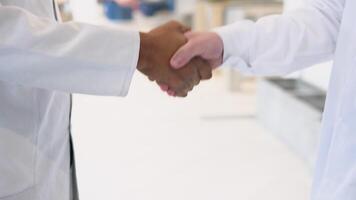 Indian and caucasian doctors in white coat handshake in a medical clinic. Close up of medical multiethnic staff handshake in a hospital hallway video