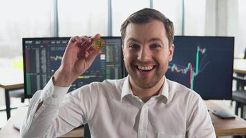 Satisfied man holding a golden bitcoin in his hand against the background of financial charts. Bitcoin growth, bullrun video