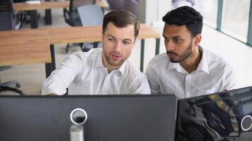 Manager consulting indian client with online technology at office meeting. Two diverse business men analysts partners talking, working together, discussing data management using computer video