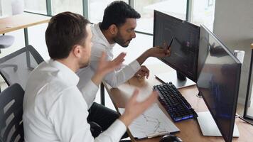 Two multiracial investors brokers analysing indexes online cryptocurrency stock. Diverse managers traders analysts discussing financial growth market at desk with pc graphs on screen video