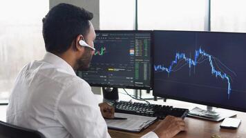 Indian business man trader investor analyst looking at financial stock market charts rate dynamic, trading data indexes growth using pc for cryptocurrency digital analytics video
