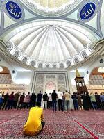 In the quiet embrace of night, worshippers gather in the grand prayer hall of the mosque, seeking solace and connection through fervent prayers. photo