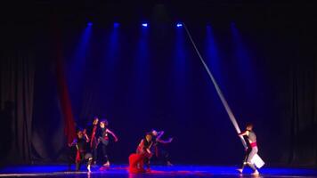 Performers on a dimly lit stage with dramatic lighting, preparing for a theatrical show or dance performance. video