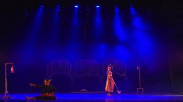 Performers on a dimly lit stage with colorful lighting, creating a mysterious theatrical ambiance. video