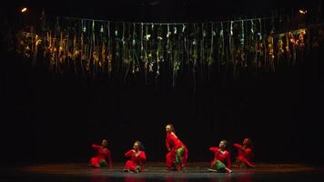 Dancers on stage with dramatic lighting and hanging ribbons creating an artistic performance atmosphere. video
