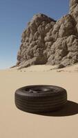 A tire laying on the sand in front of a rock formation video