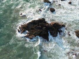 Aerial View of Rugged Coastal Rocks Bathed in Foamy Waves in Mazunte, Mexico photo