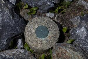 A Survey Marker Embedded in Rocks on a Mountain Trail photo