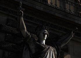 A Close-Up View of a Stone Statue Holding a Torch at Dusk in Paris, France photo